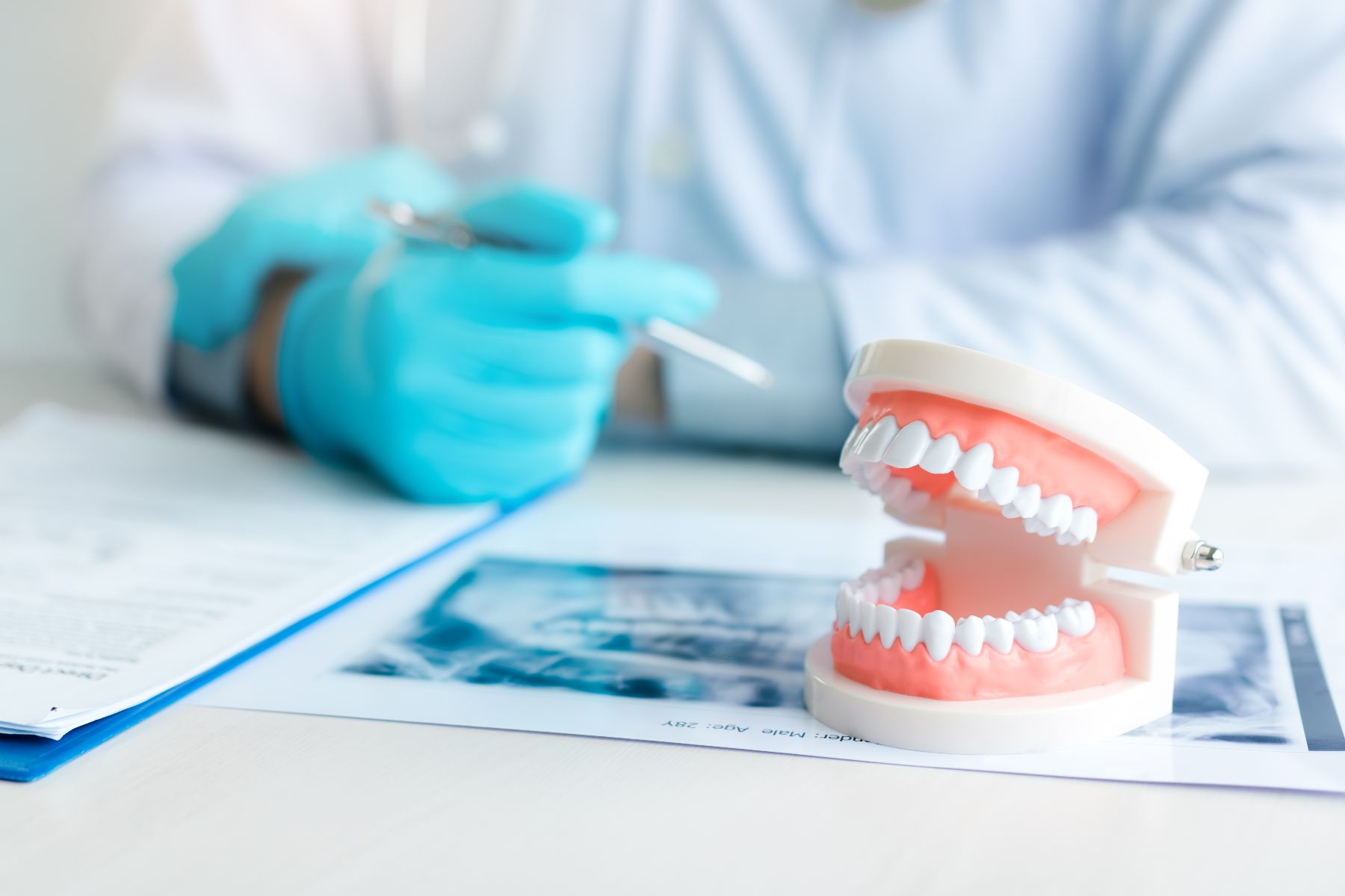 dentures on desk and dentist with blue gloves